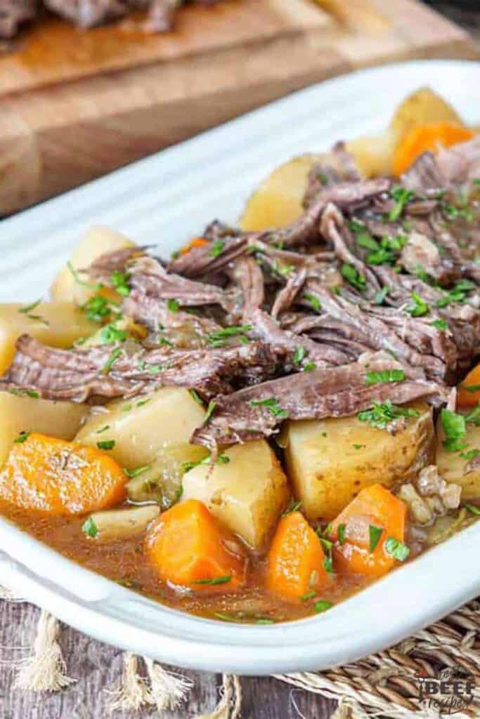 Shredded slow cooker roast beef with potatoes and carrots on a white dish