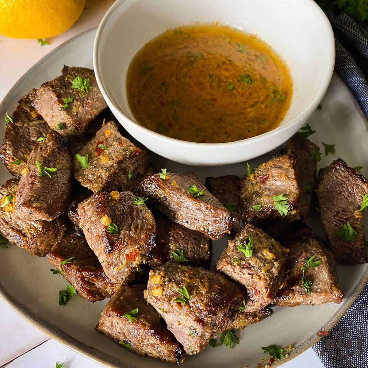 air fryer steak bites on a plate with a bowl of cowboy butter