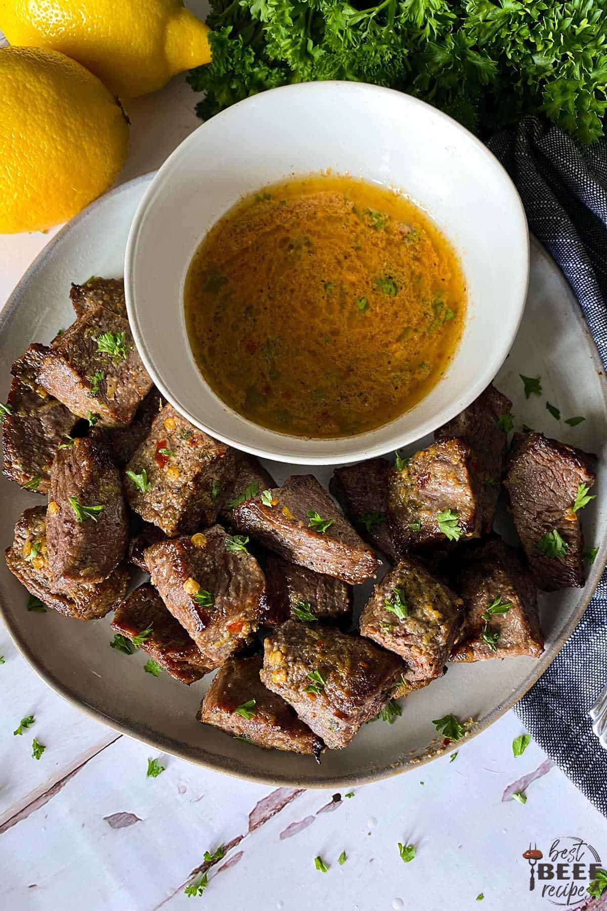 Air fryer steak bites on a plate with a bowl of cowboy butter