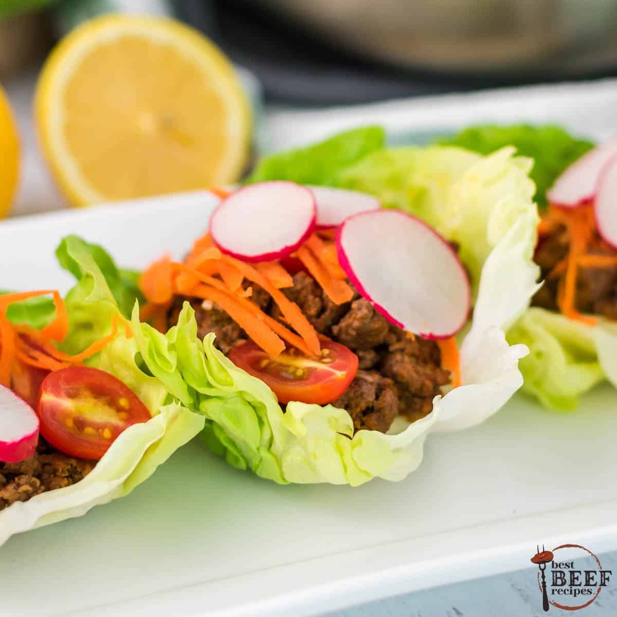 three ground beef lettuce wraps side by side on a white platter