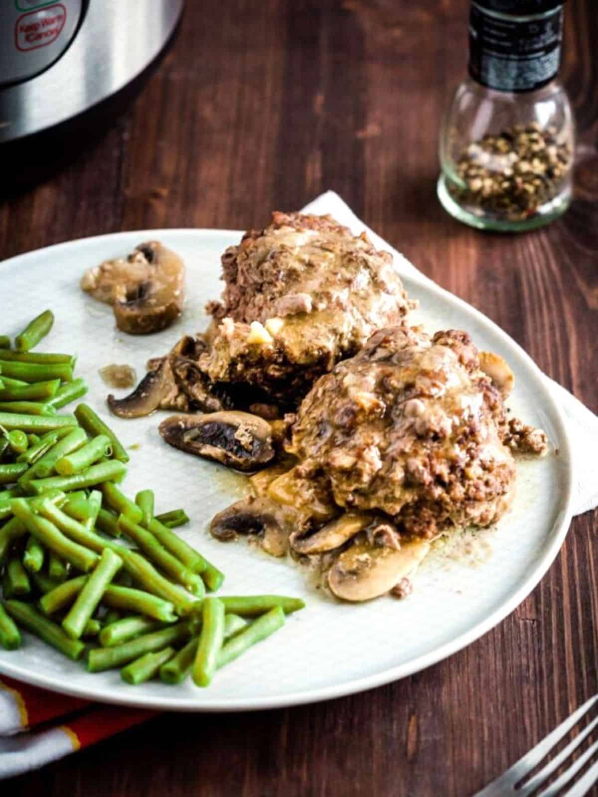Salisbury Steak with green beans on a white plate.