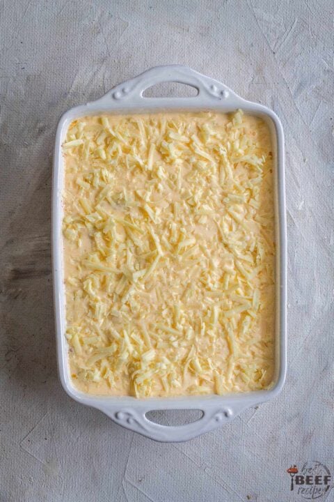 Cheese and egg mixture on top of ground beef in baking dish