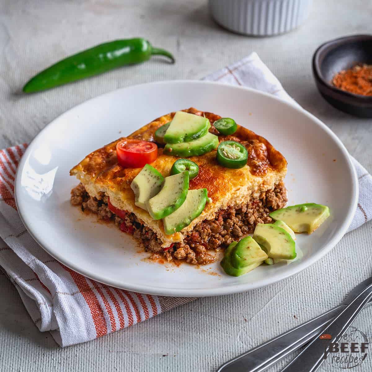 Keto taco casserole sliced onto a plate with avocados