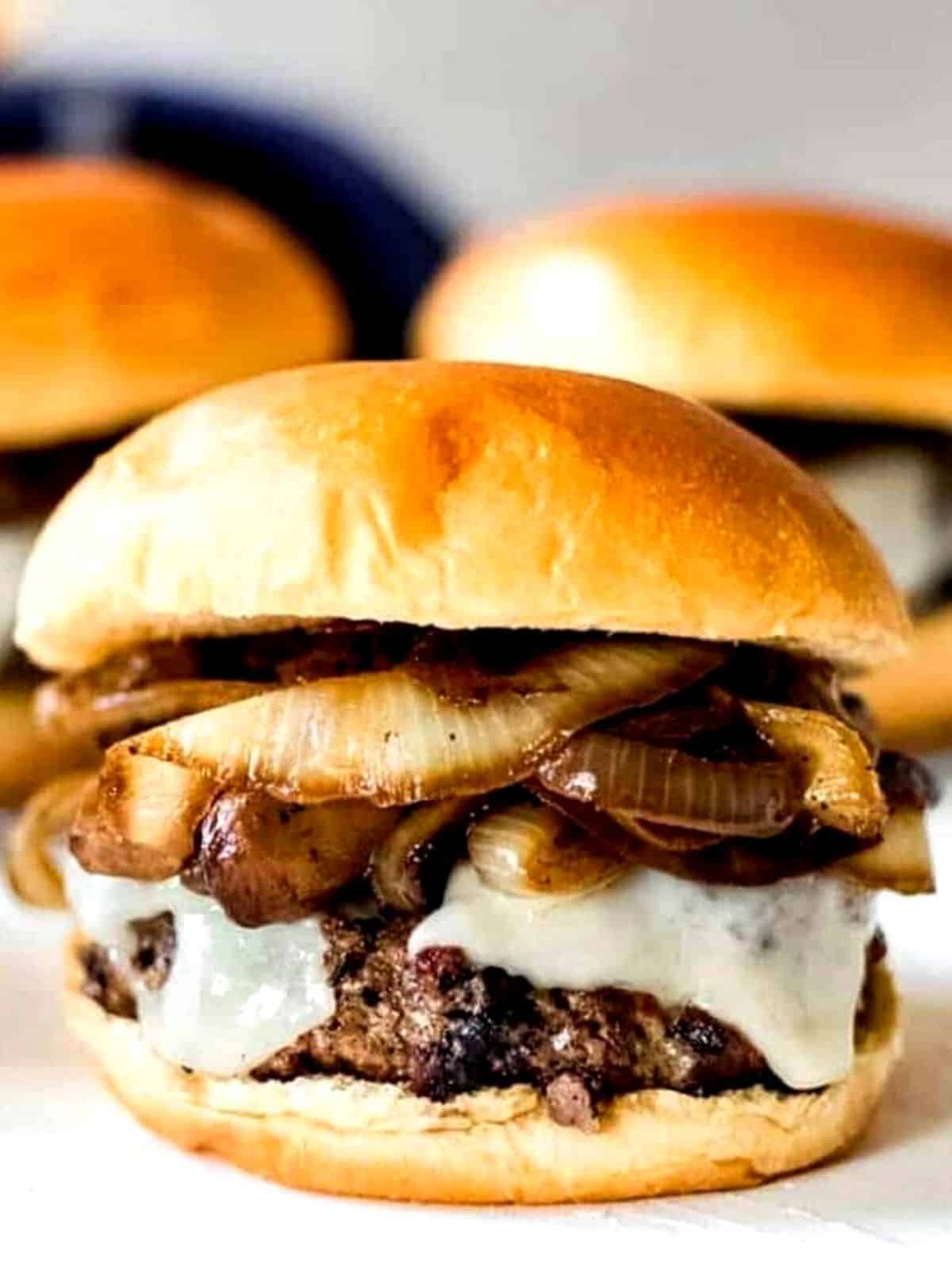 Burger with cheese, onions and mushrooms on a bun.
