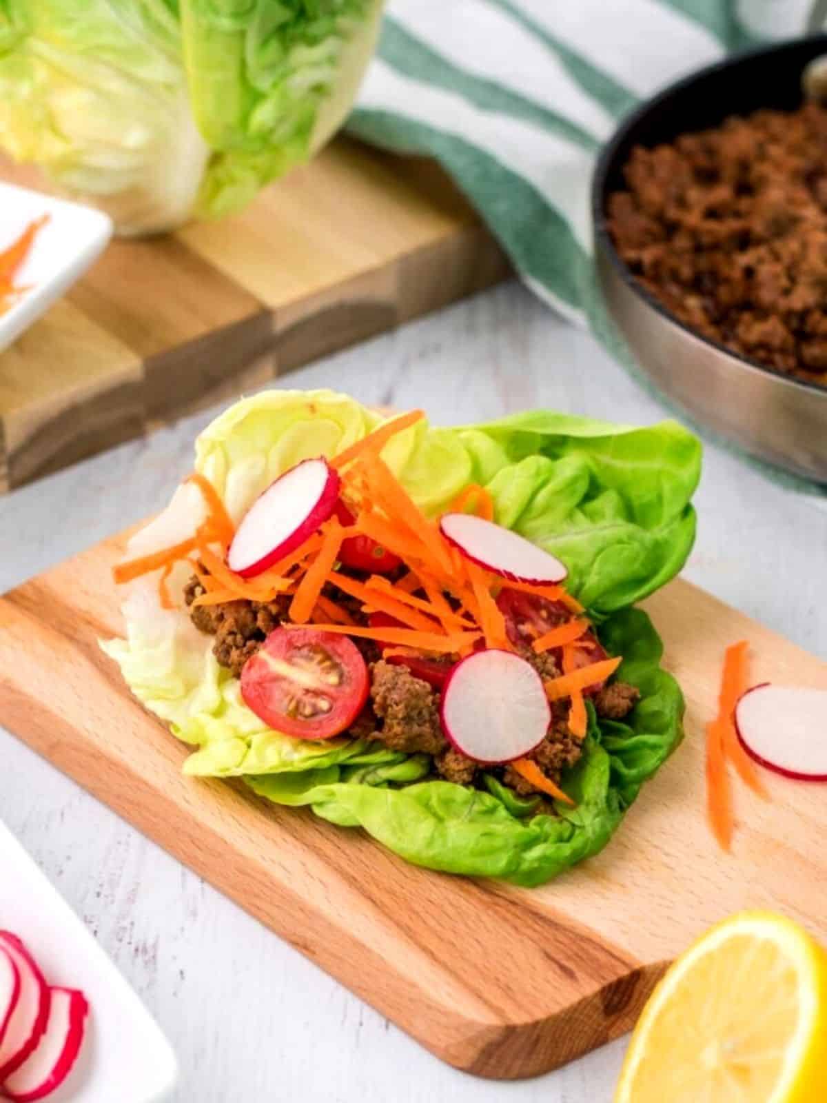 Ground beef in a lettuce wrap with carrots and raddishes.