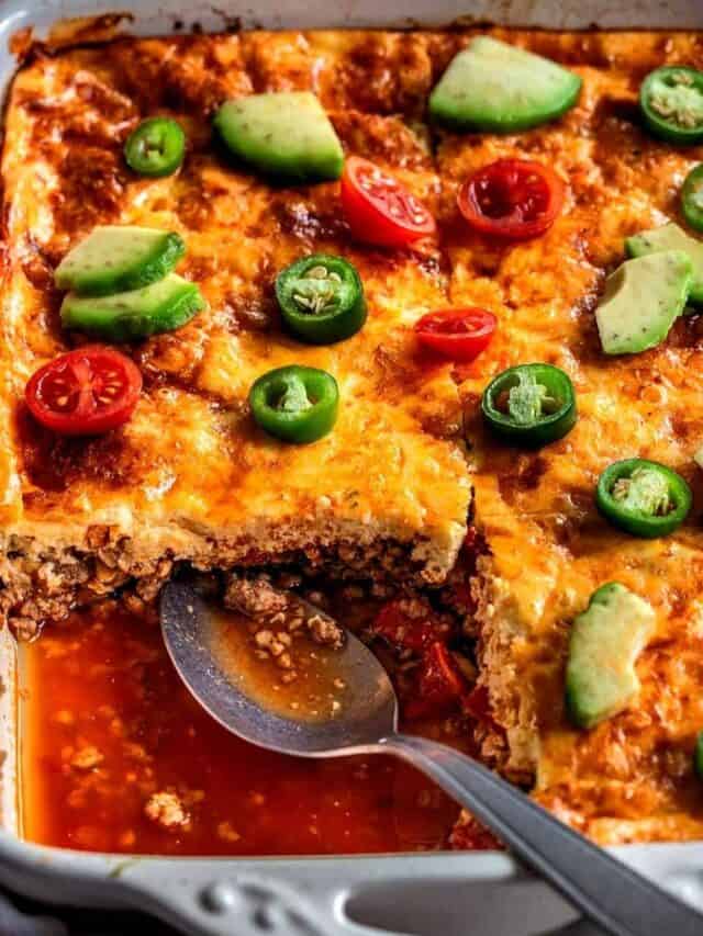 Taco casserole in a baking dish with one portion taken out.