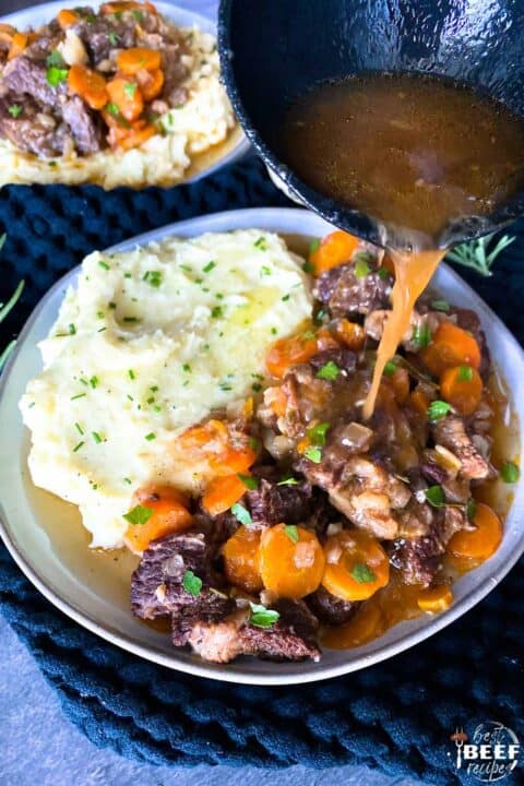 Pouring sauce over beef short ribs on plate with mashed potatoes