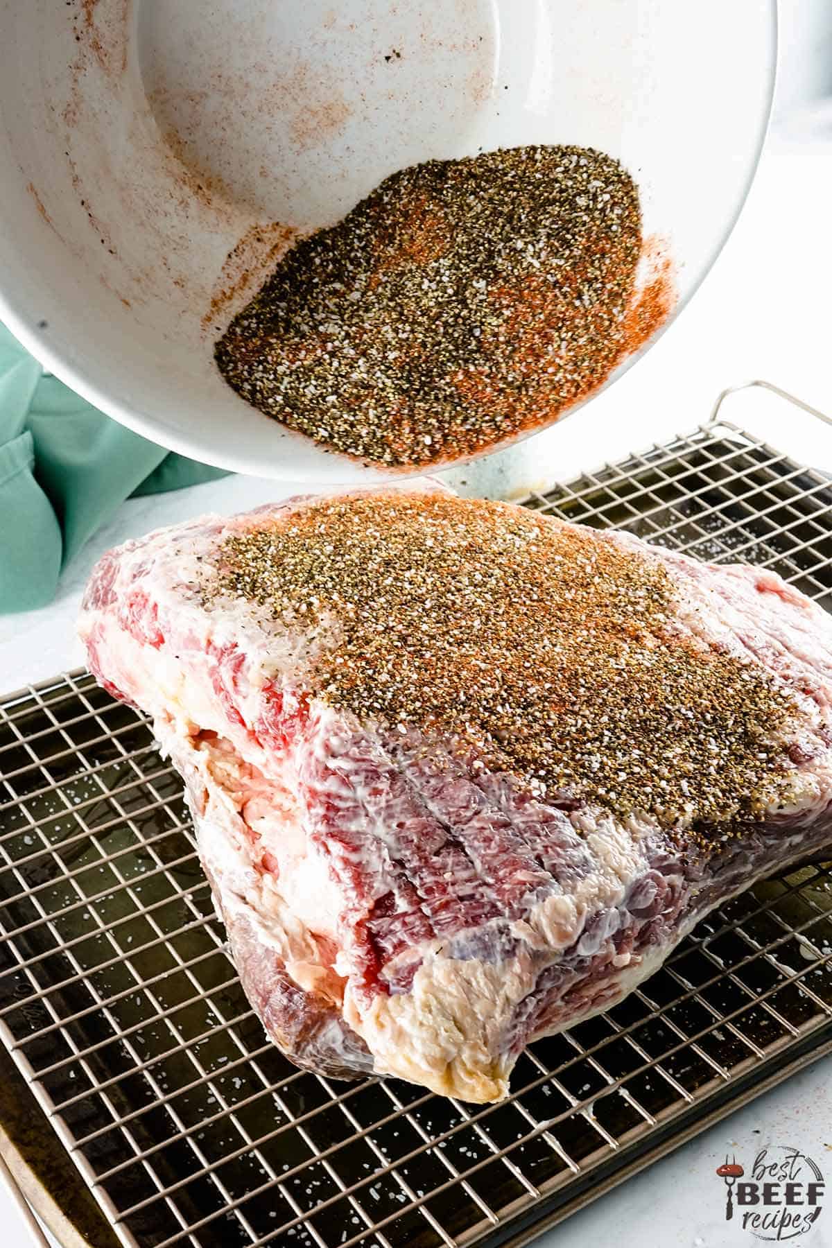 pouring seasoning onto brisket