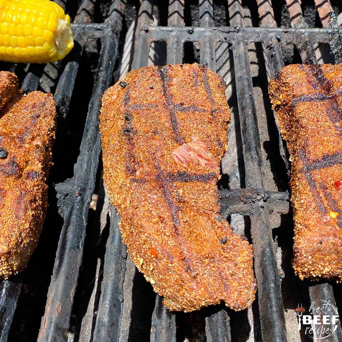 Three seasoned steaks on the grill