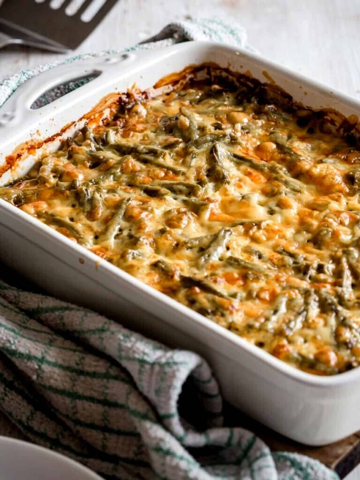 Casserole in a white dish with cheese and green beans.