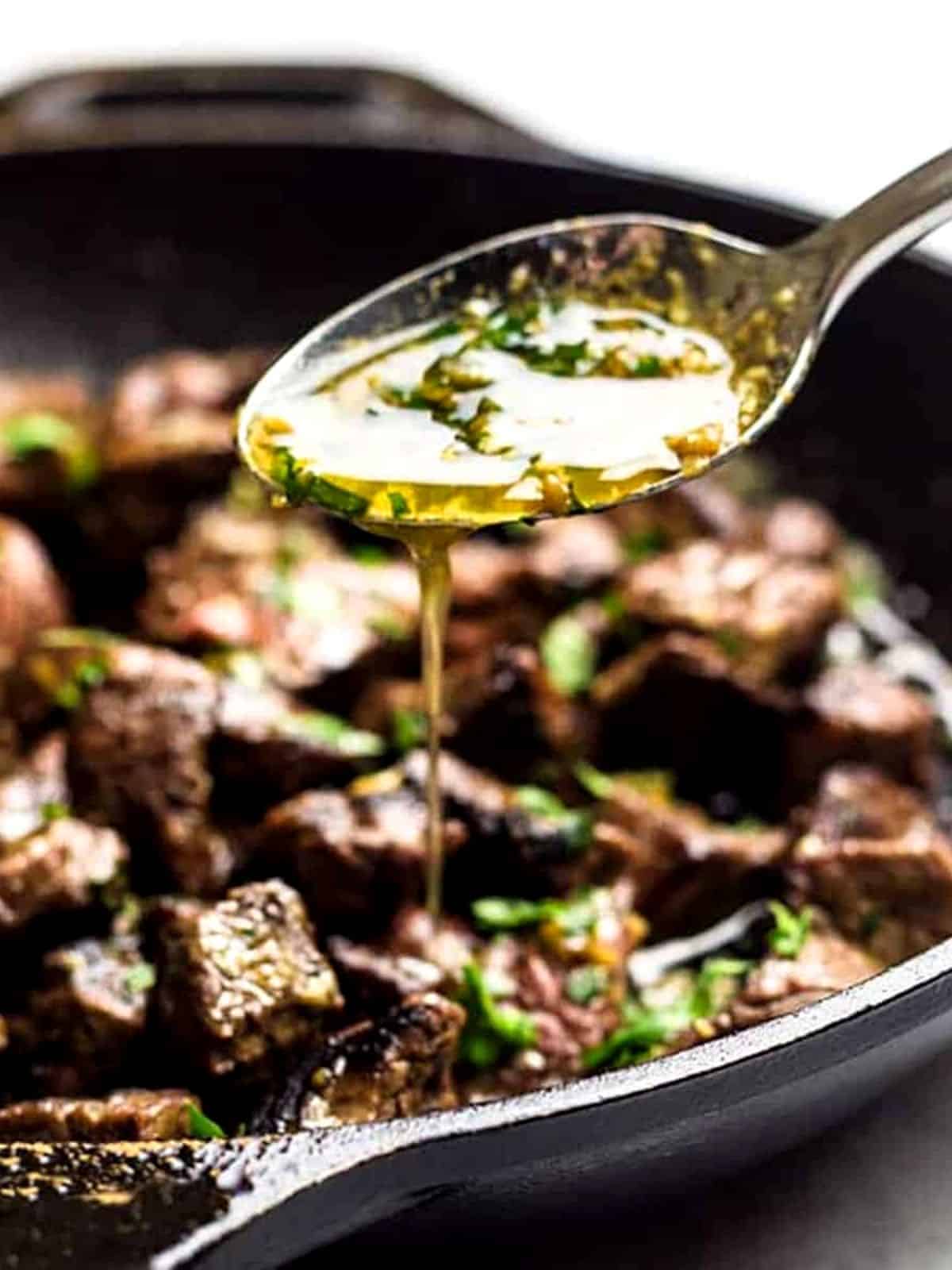 Steak bites being topped with melted butter.