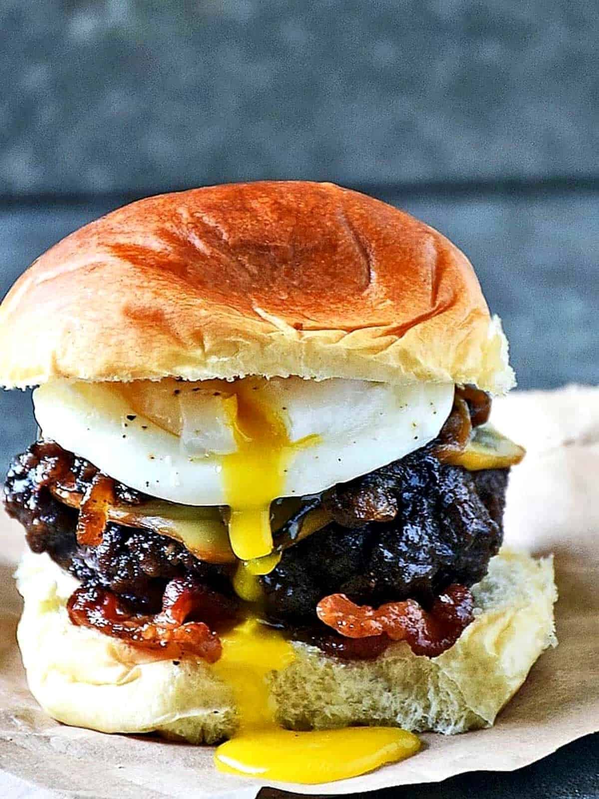 Burger with a bun, onions and a runny egg.