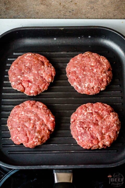 cooking four burger patties on a grill pan