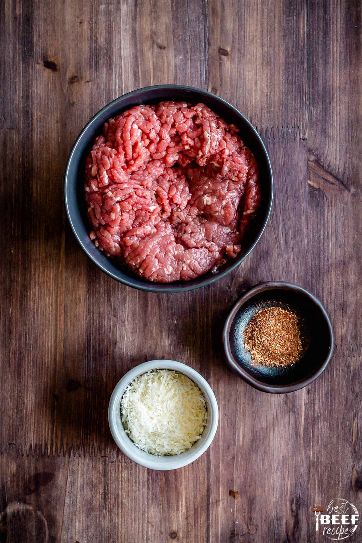 Ground beef, parmesan, and seasoning in bowls