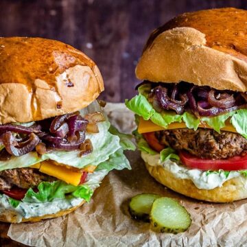 Two loaded burgers on a piece of parchment paper
