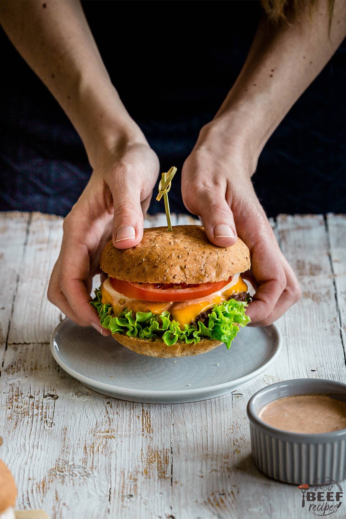 Holding a smash burger in hands over a plate