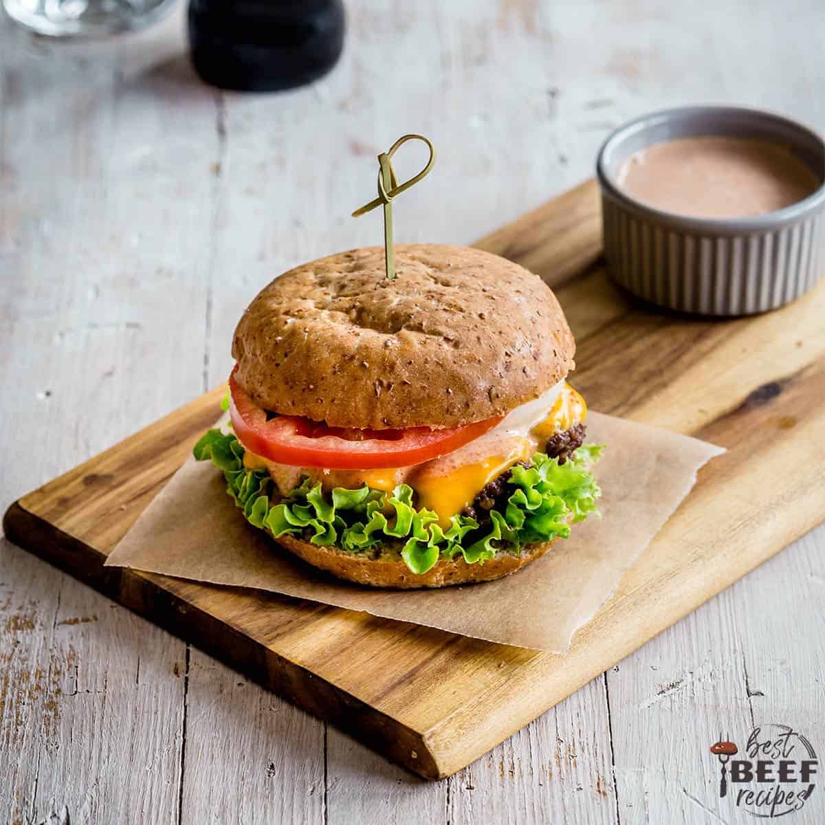 Smash burger on a cutting board with burger sauce to the side