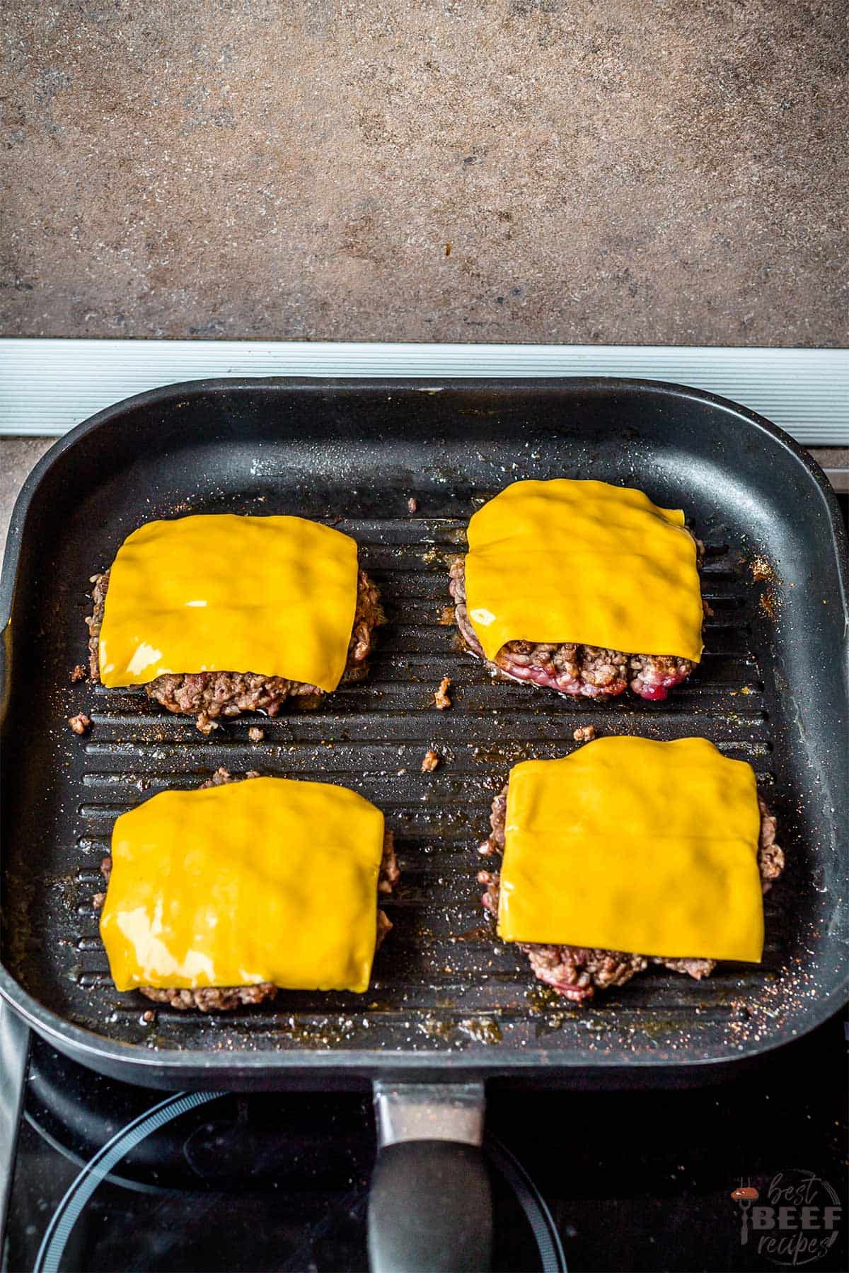 Smash burgers on the grill pan with cheese on top