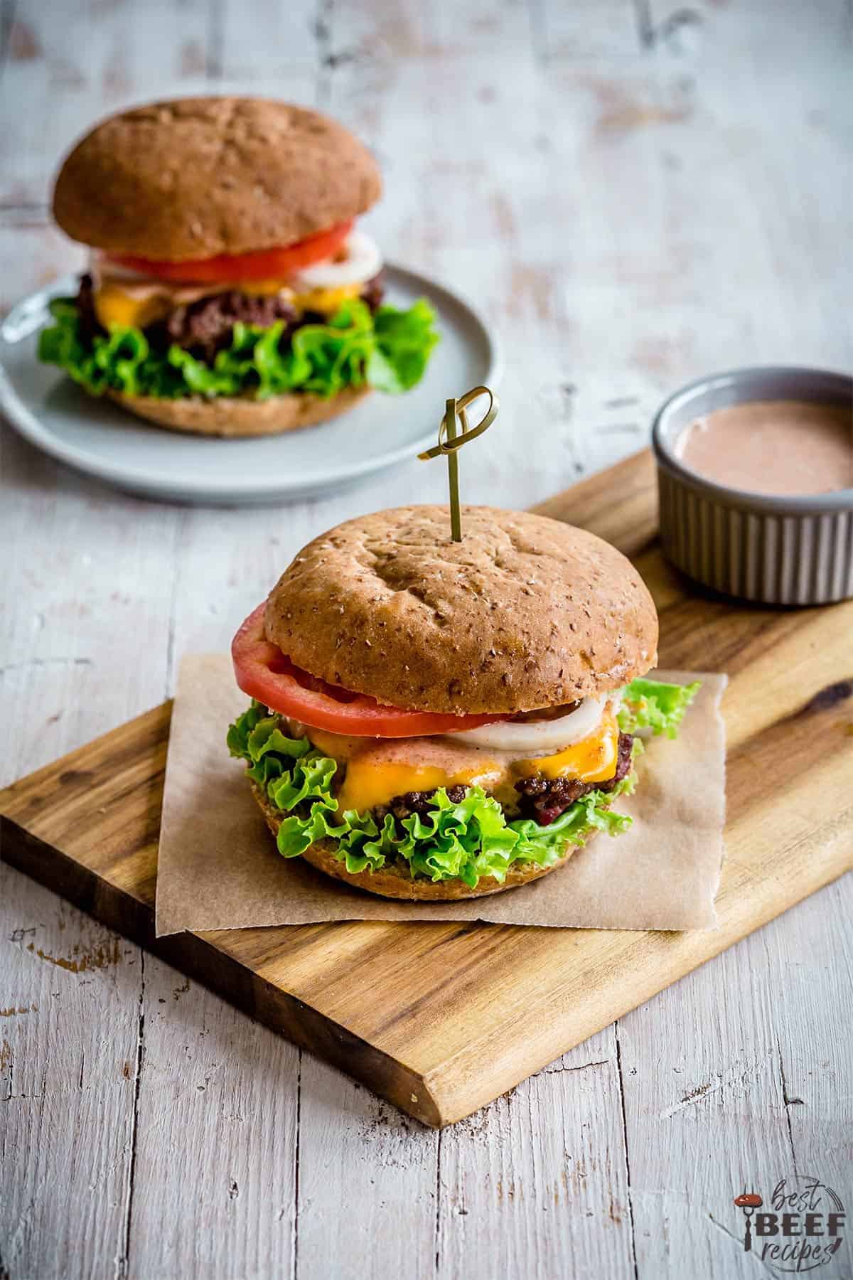 Burger on a bun with lettuce, cheese, tomato and burger sauce.