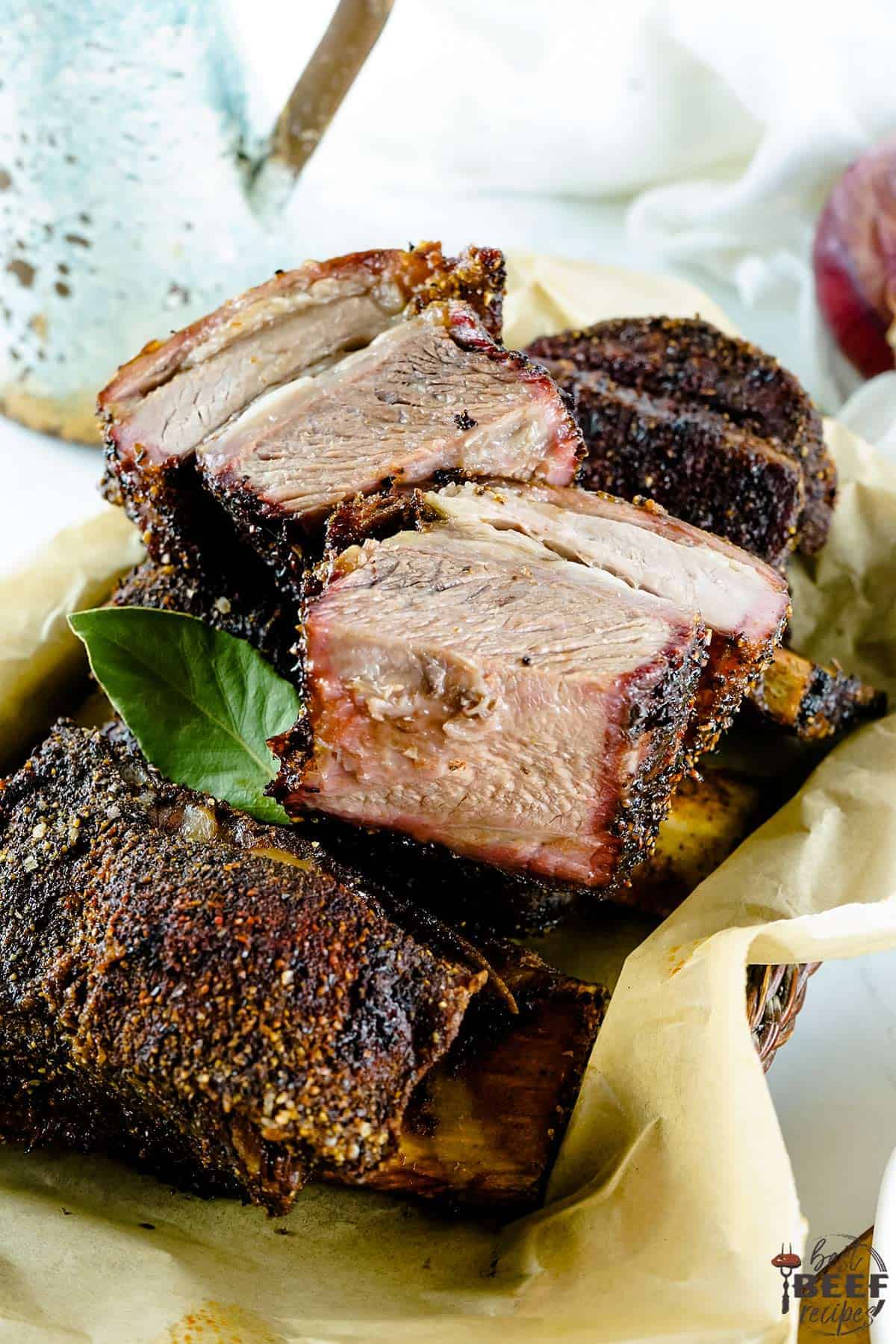 Smoked beef short ribs sliced on parchment paper in a basket