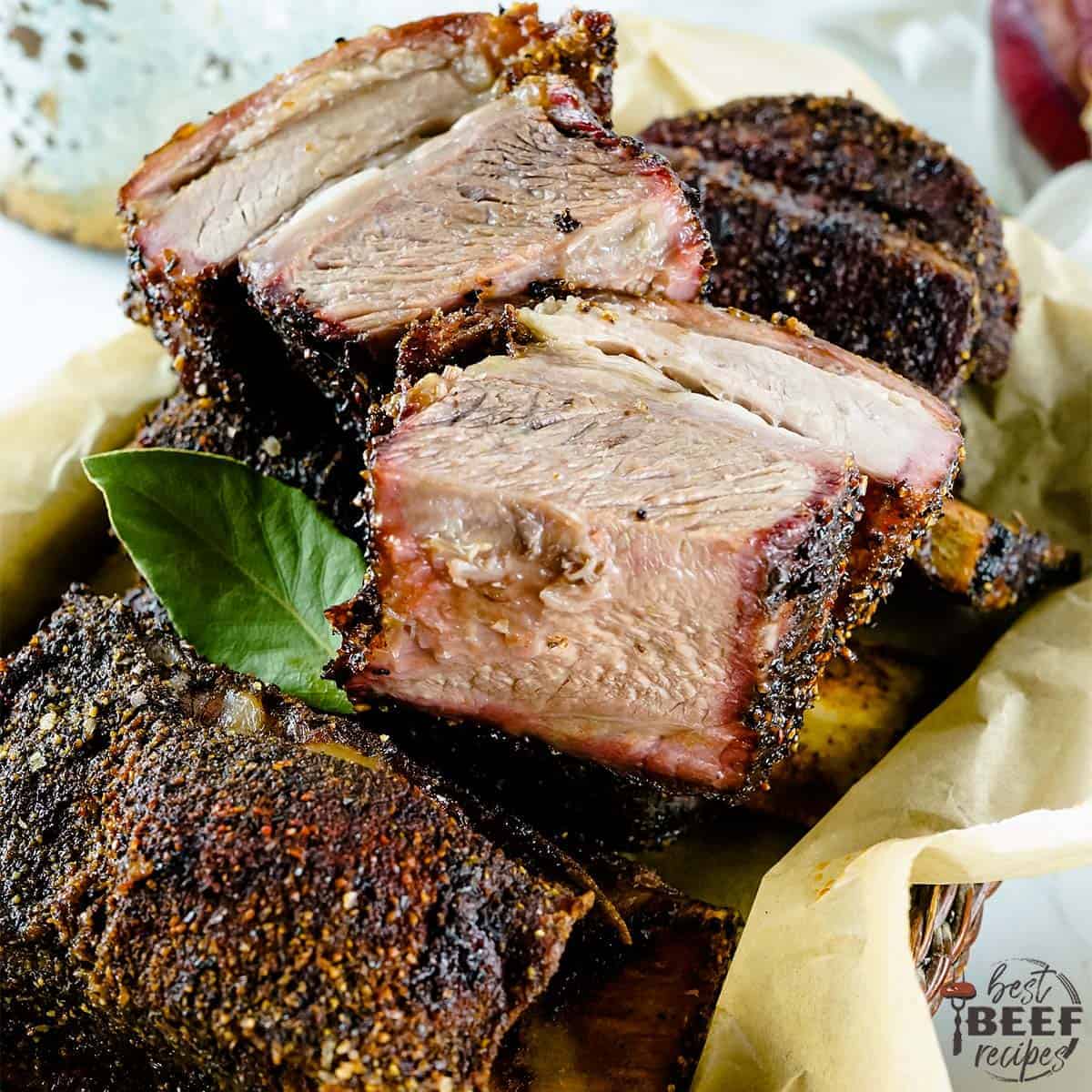 Smoked beef short ribs sliced on parchment paper in a basket