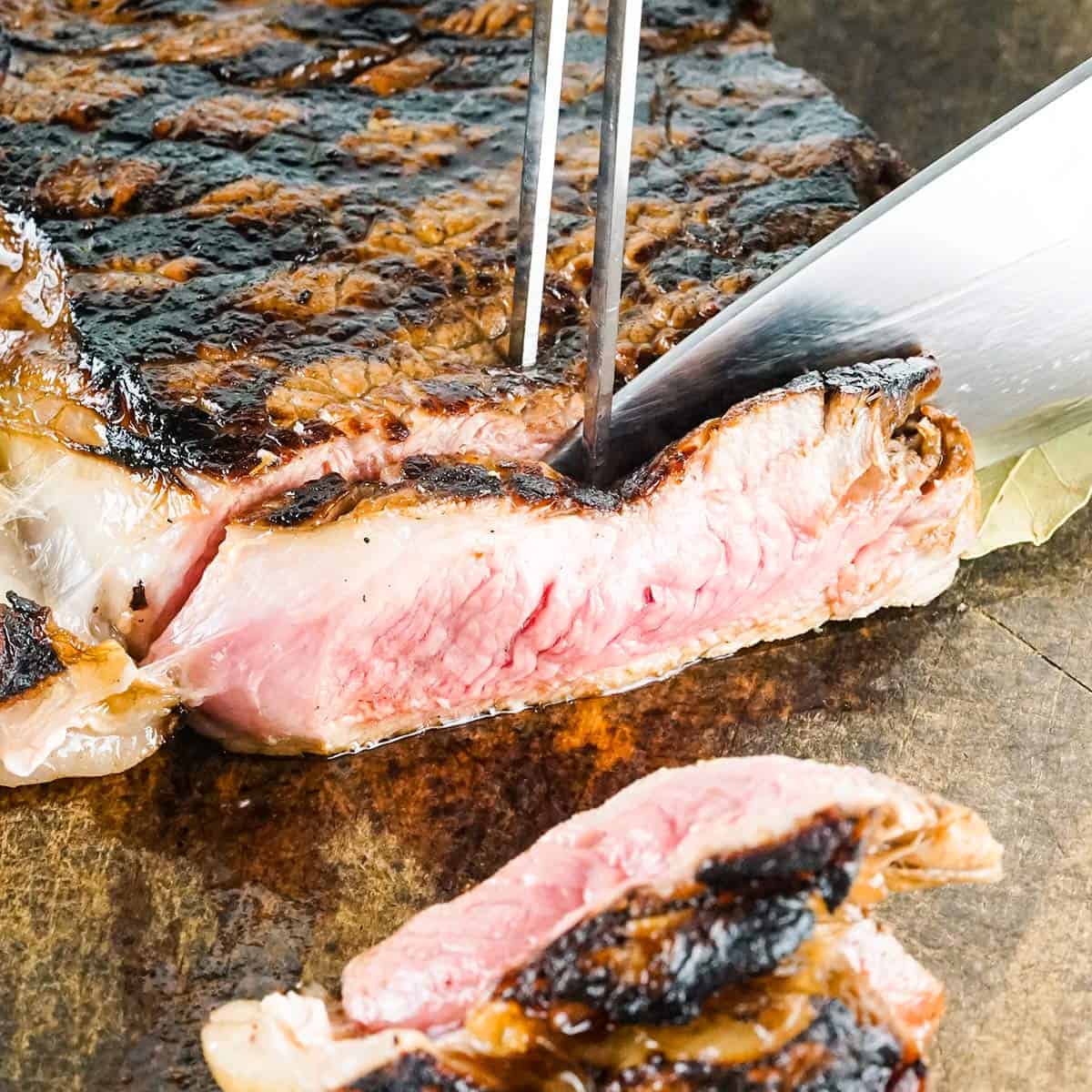 slicing new york strip steak on a cutting board