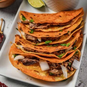 Beef birria tacos on a white platter