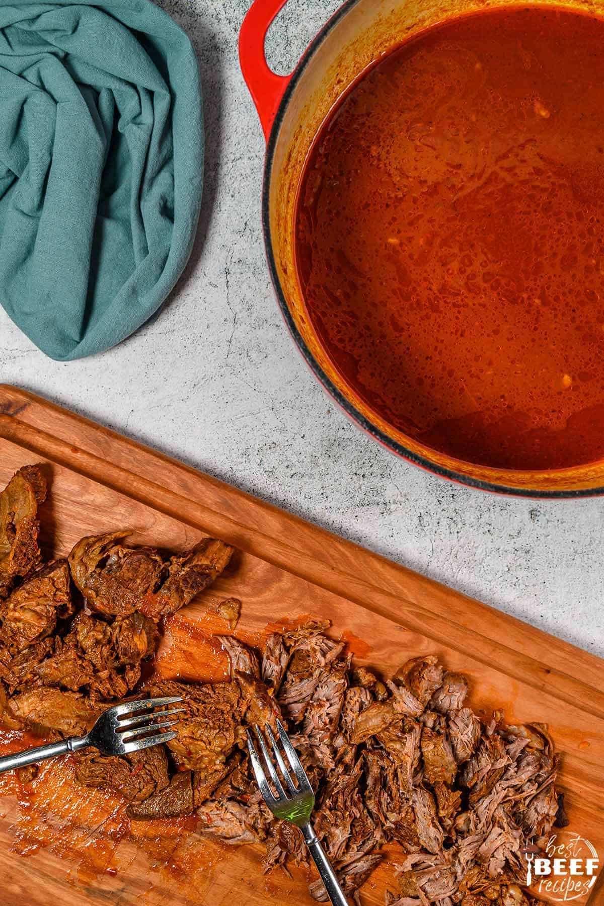 Beef birria stew meat next to a dutch oven of the stew