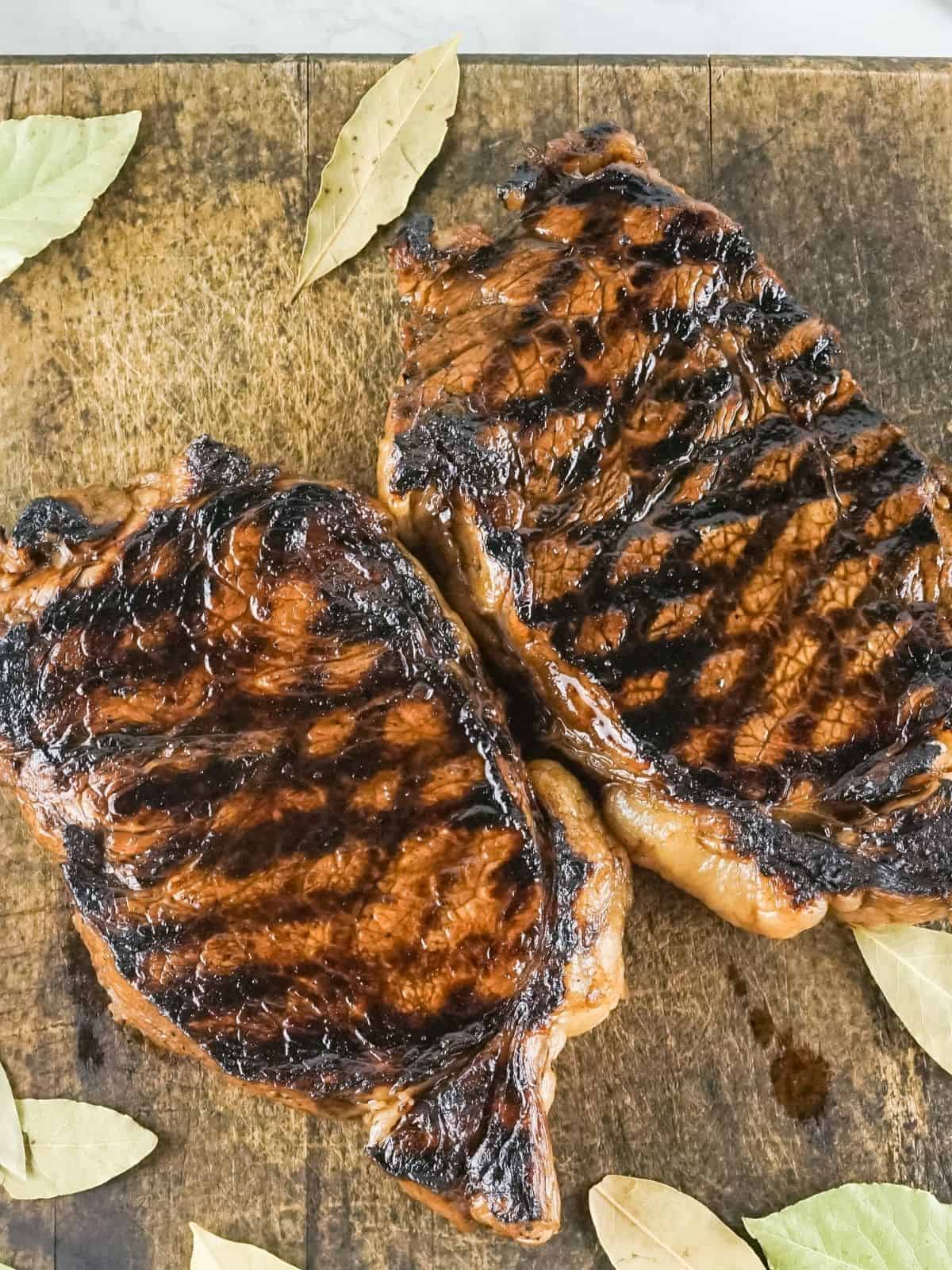 Two grilled steaks on a cutting board.