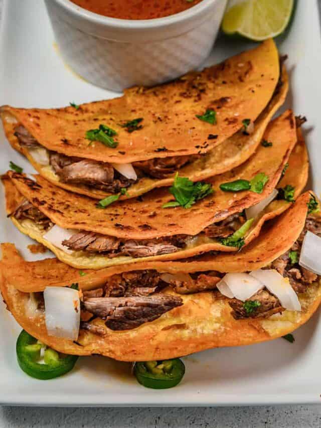 Beef birria tacos on a white platter with birria stew in a bowl