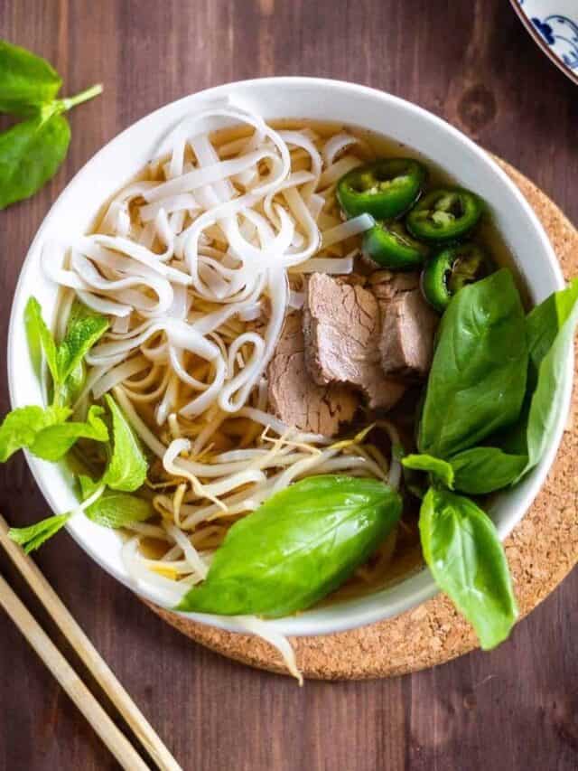Beef pho in a bowl with rice noodles and jalapeños.