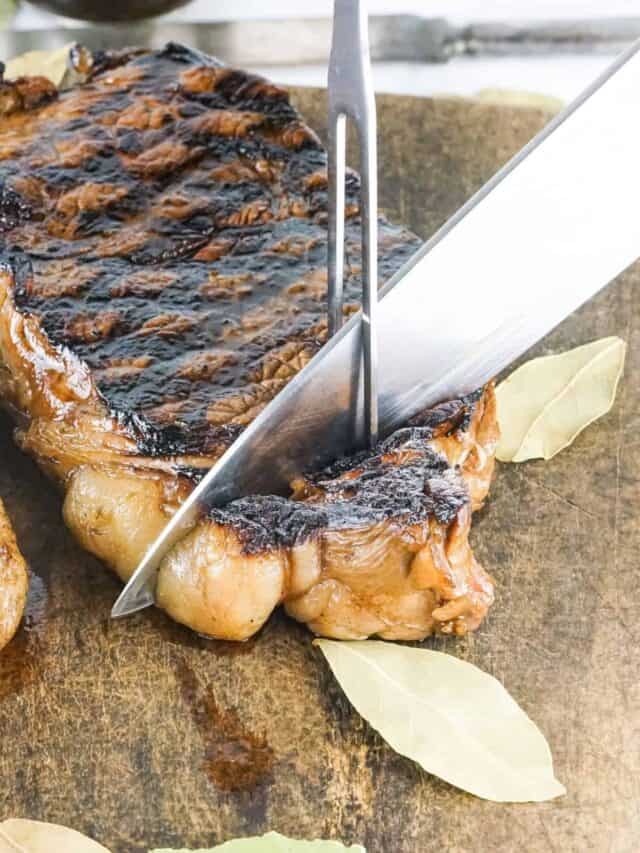 Strip steak grilled being sliced by a knife.