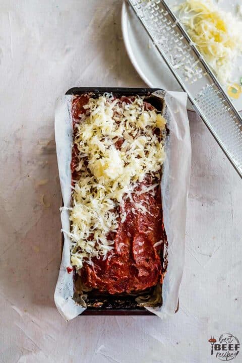 Adding more cheese to keto meatloaf during baking process
