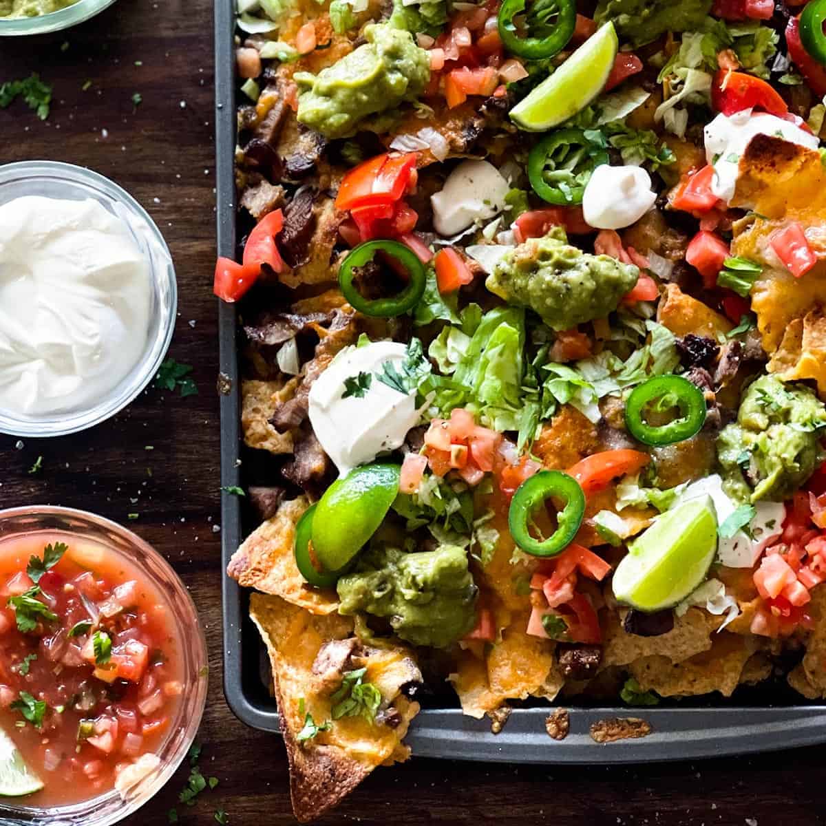 sheet pan nachos with sour cream and salsa to the side