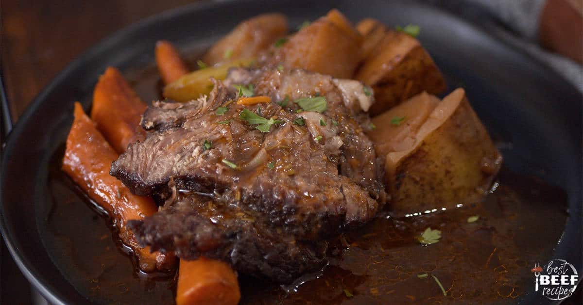 Chuck roast cut into slices with carrots and potatoes ion a plate up close