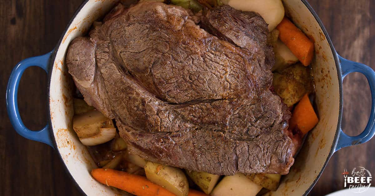 Beef chuck roast on top of vegetables in a dutch oven