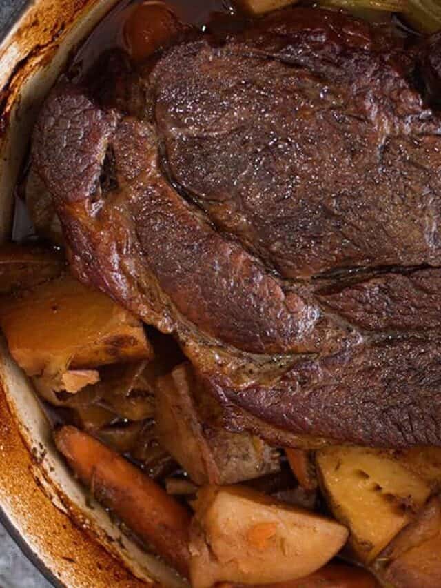 Beef chuck roast on top of vegetables in a dutch oven cooked
