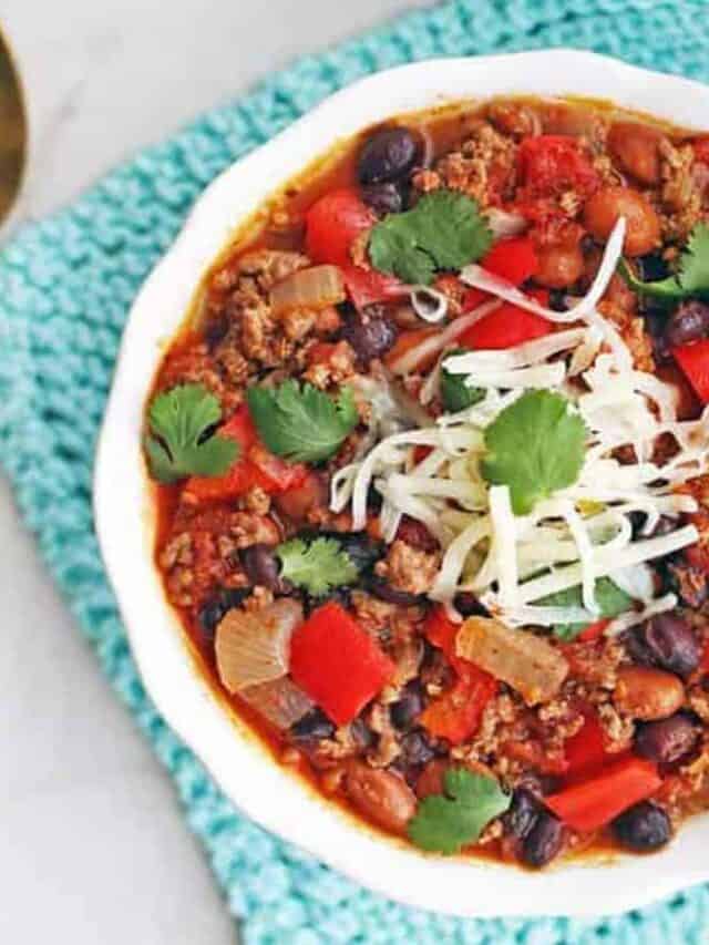 Ground beef chili in a white bowl with a spoon