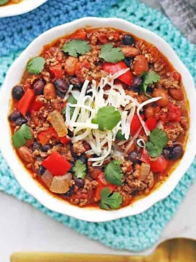 Ground beef chili in a white bowl with a spoon