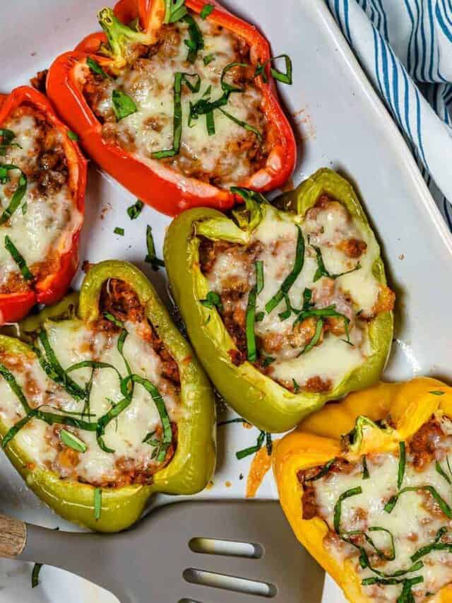 Five stuffed bell peppers on a white platter