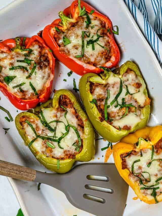 Five stuffed bell peppers on a white platter