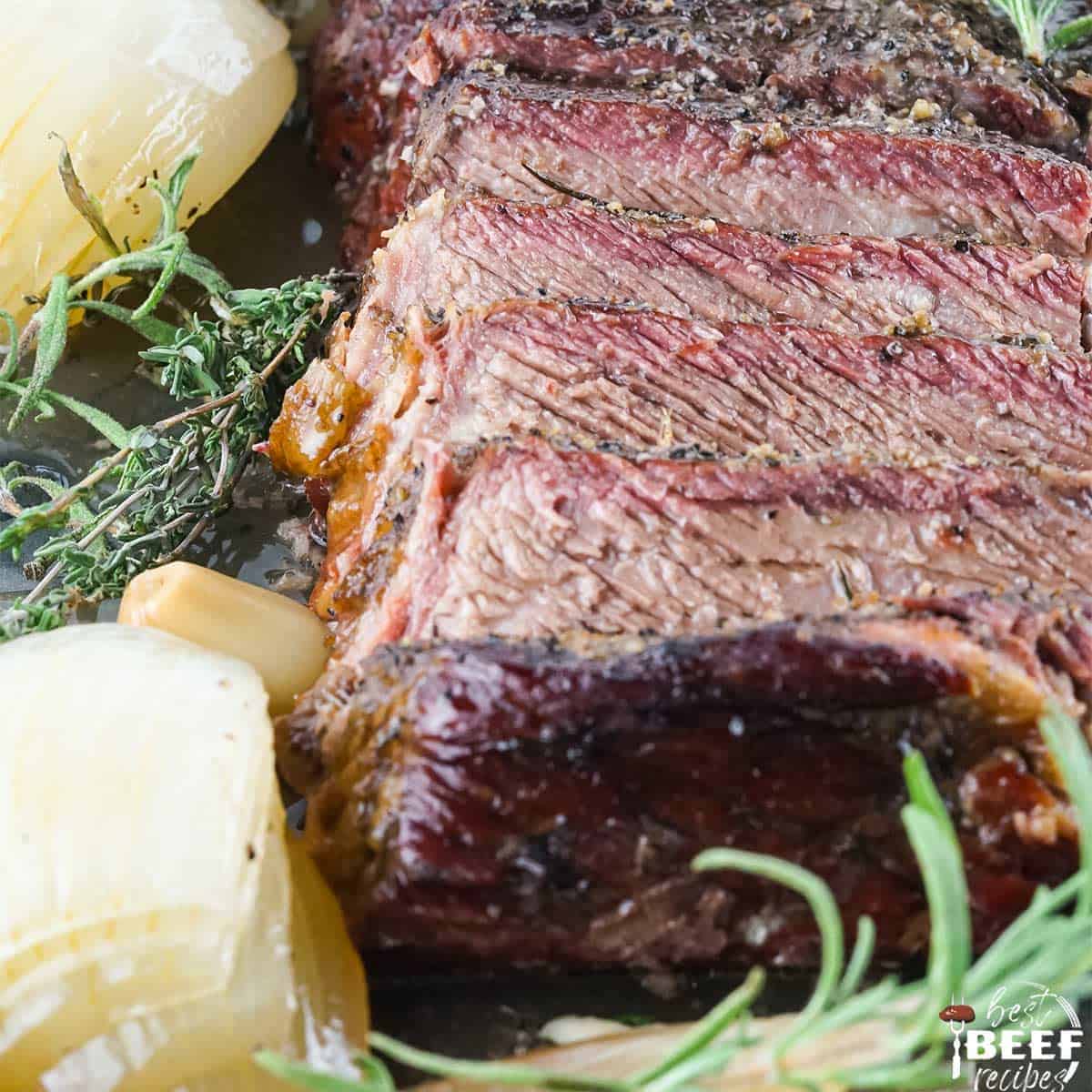 Slices of smoked chuck roast beef with onions and fresh herbs