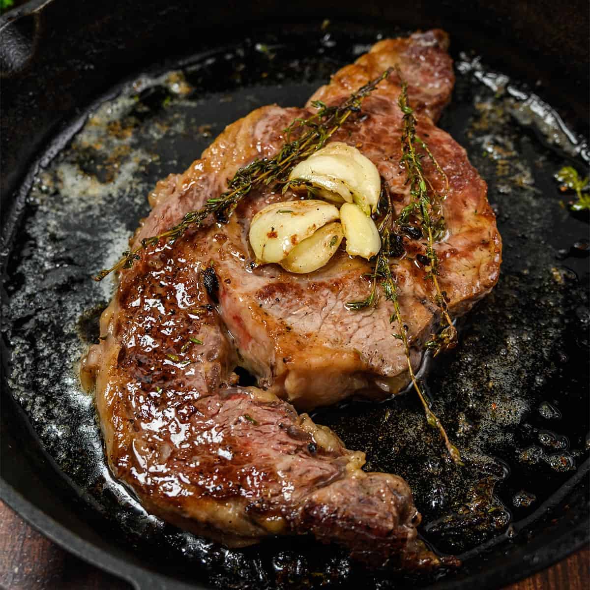 steak cooking on a cast iron skillet