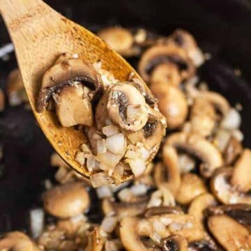 Steakhouse mushrooms in a skillet with a wooden spoon