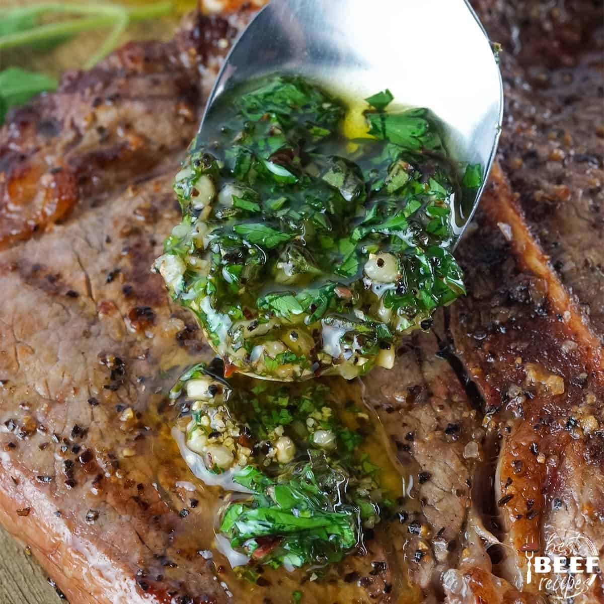 Pouring chimichurri sauce on to steak with a spoon