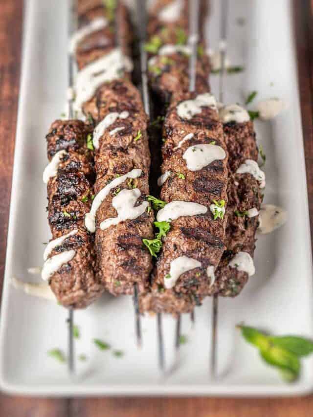 Beef kofta kebabs with garlic sauce on a white platter