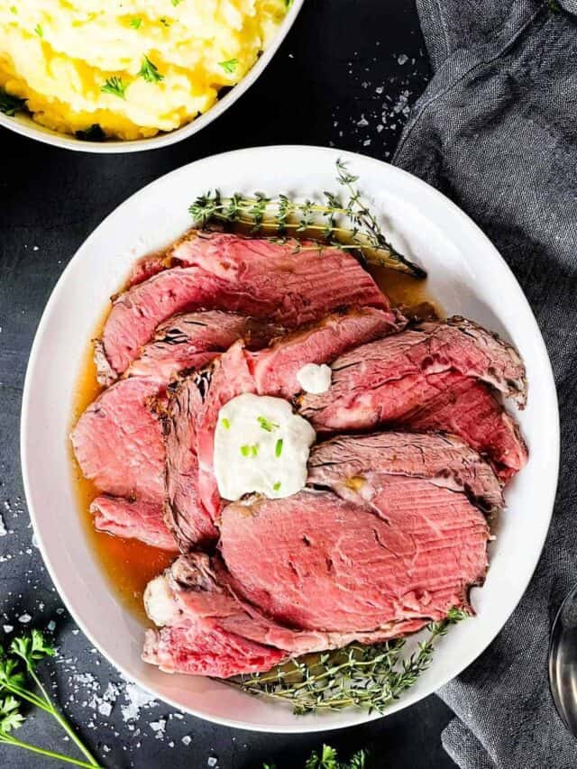 Sous Vide prime rib cut into slices on a plate with Au Jus and horseradish sauce.