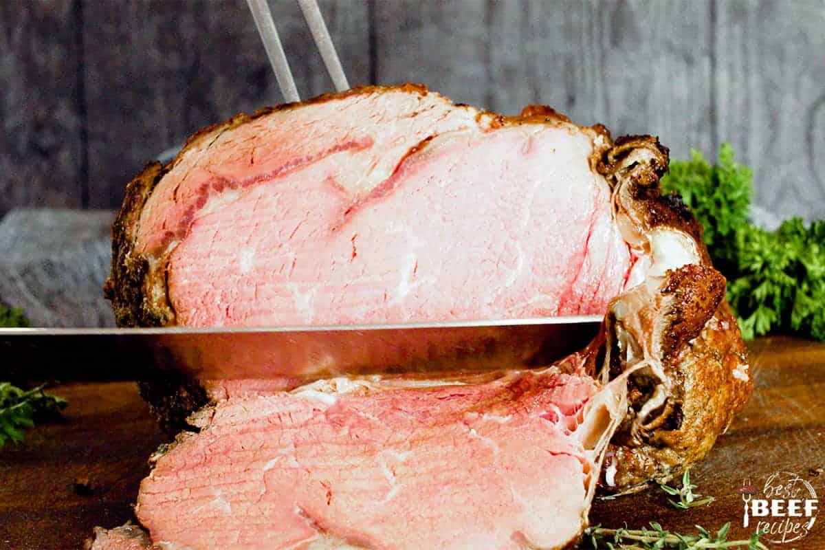 Slicing prime rib on a cutting board with a sharp knife