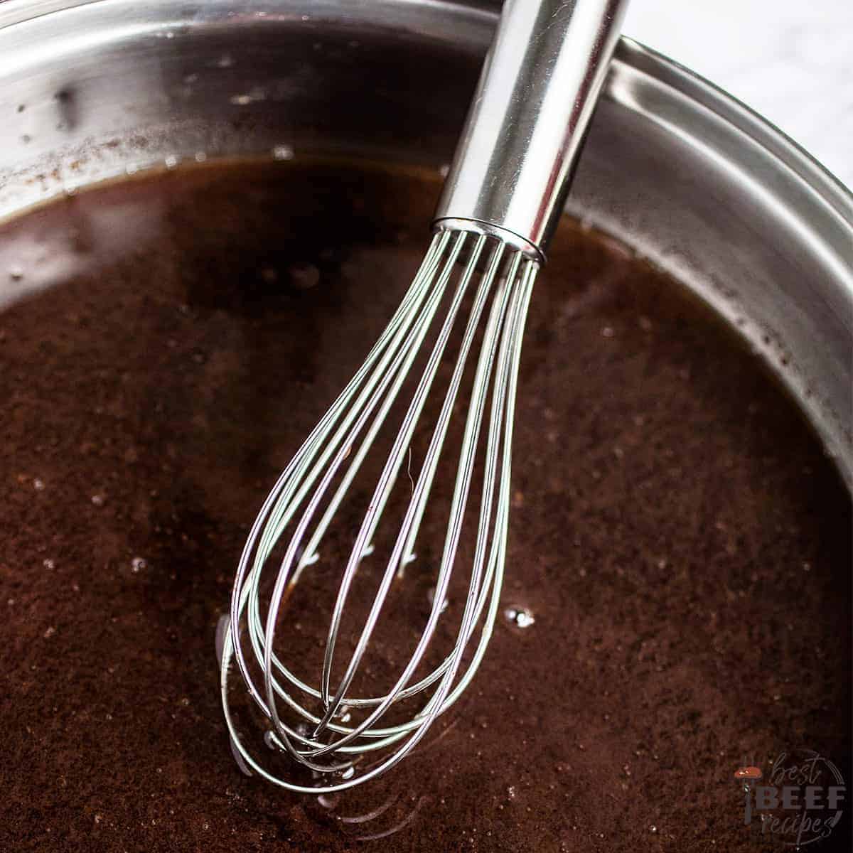 au jus sauce for prime rib in a metal bowl with a whisk