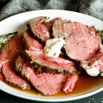 sliced prime rib on a plate served with horseradish sauce